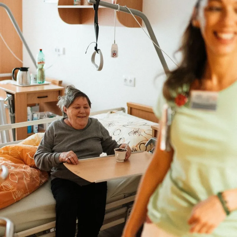 A caregiver checking in with a smiling patient during post-hospital recovery